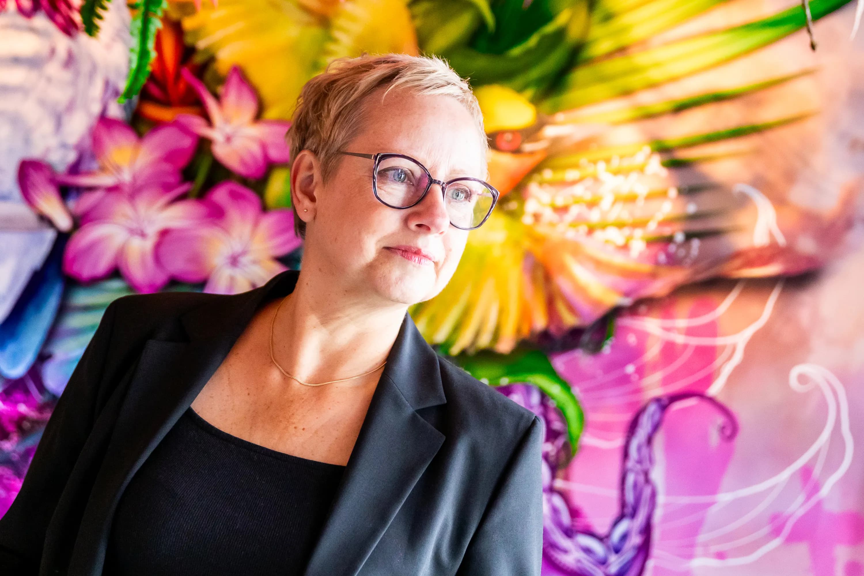 Joke van der Kraan, grafisch vormgever en eigenaar van VormBuilders, gefotografeerd in het stedelijke landschap van Rotterdam, waar haar professionele uitstraling en warme persoonlijkheid vastgelegd zijn tegen een achtergrond van dynamische architectuur.