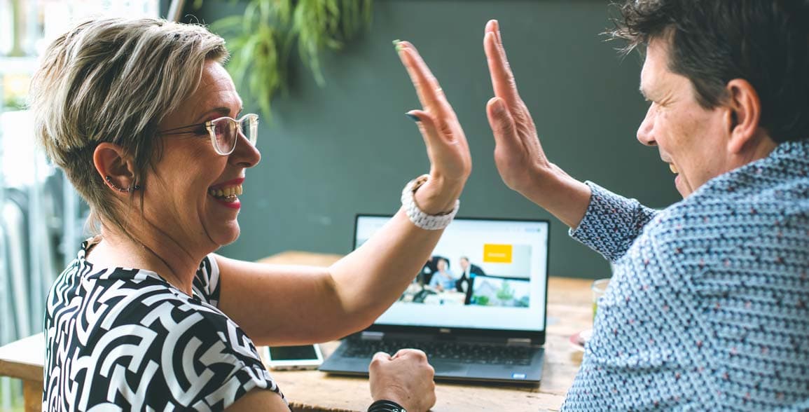 Twee collega’s vieren een geslaagd samenwerkingsmoment