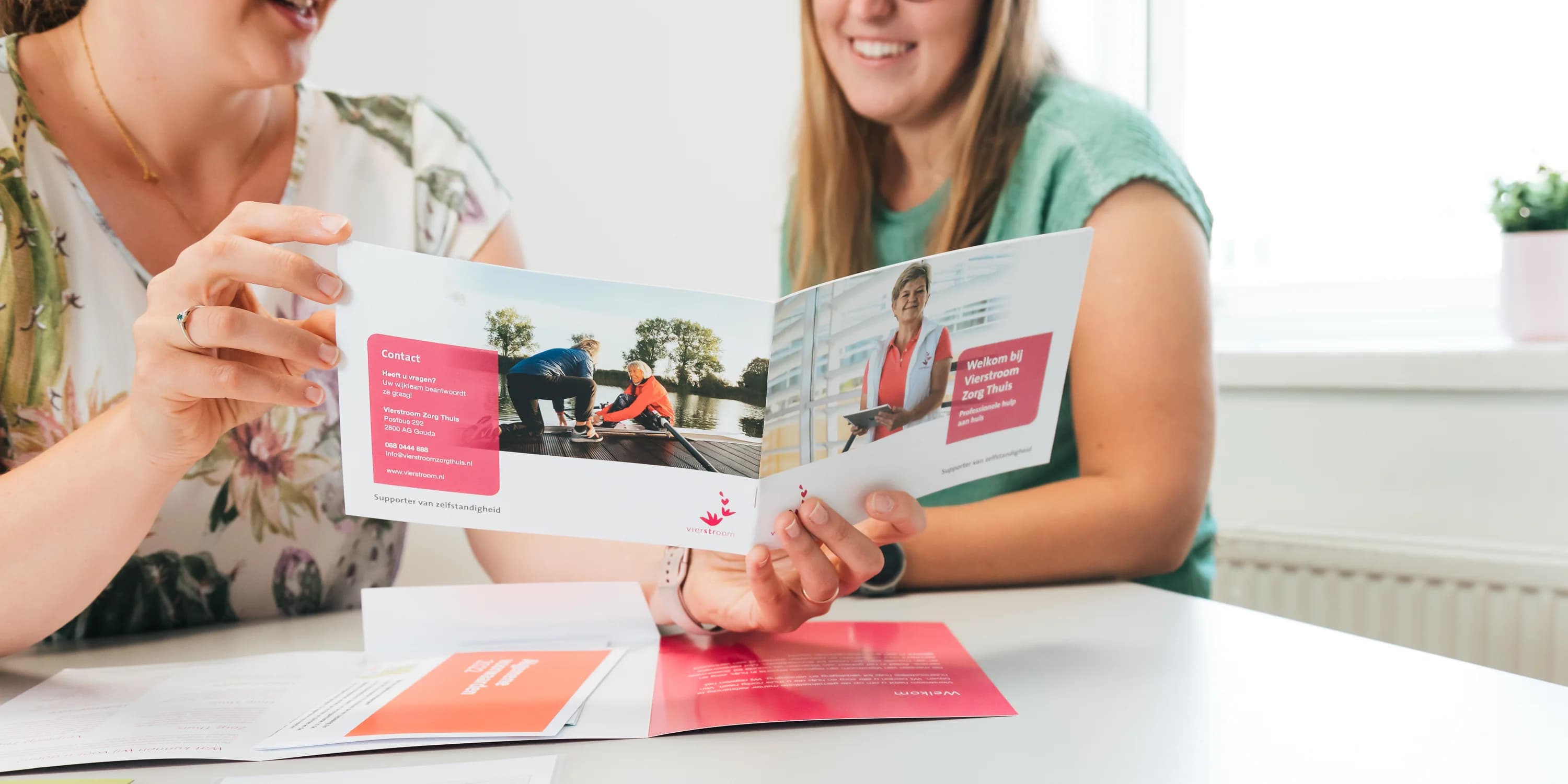 Collega’s bekijken samen communicatiemateriaal tijdens hun werk