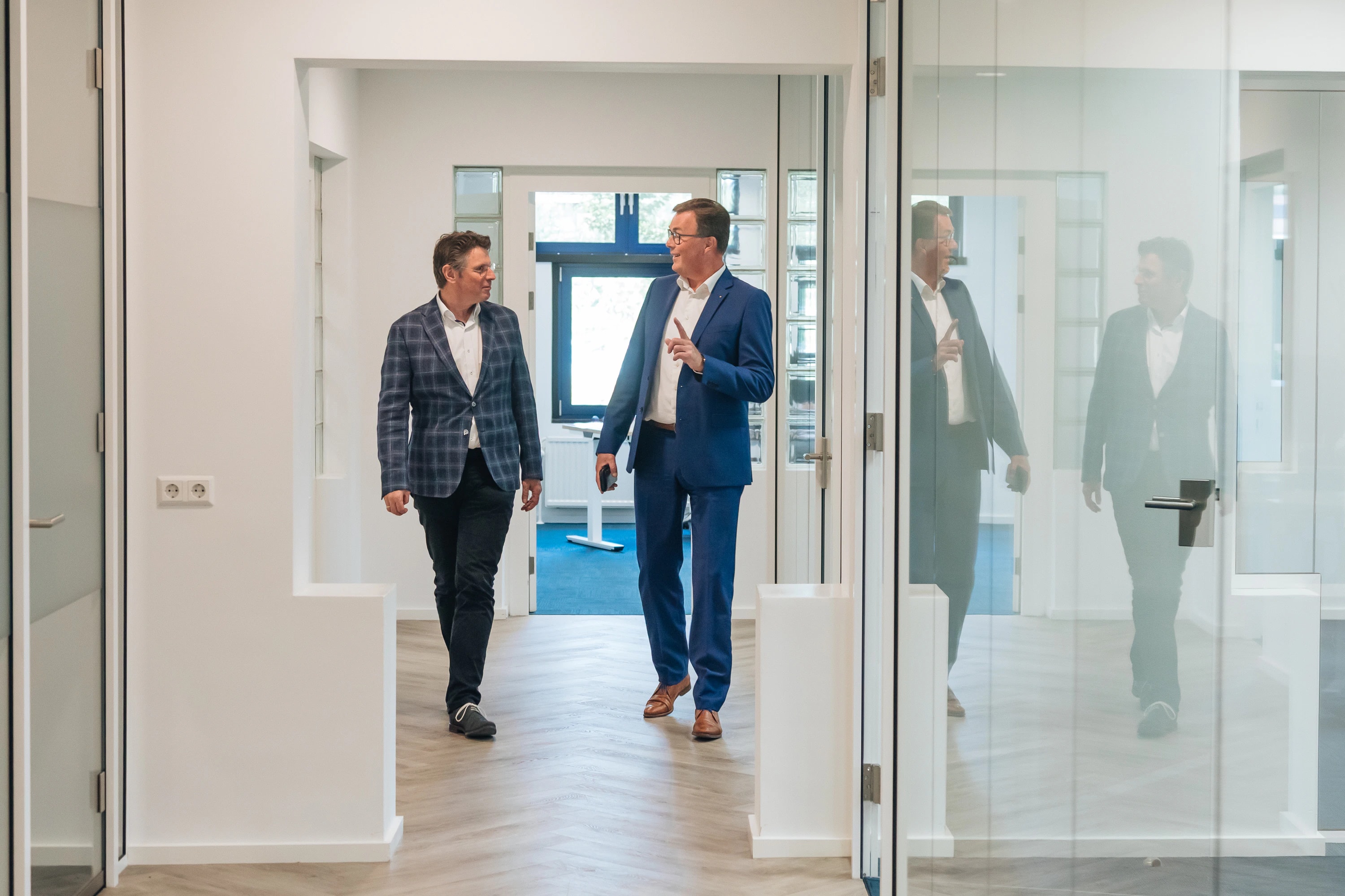 Twee collega’s lopen samen door een lichte kantooromgeving