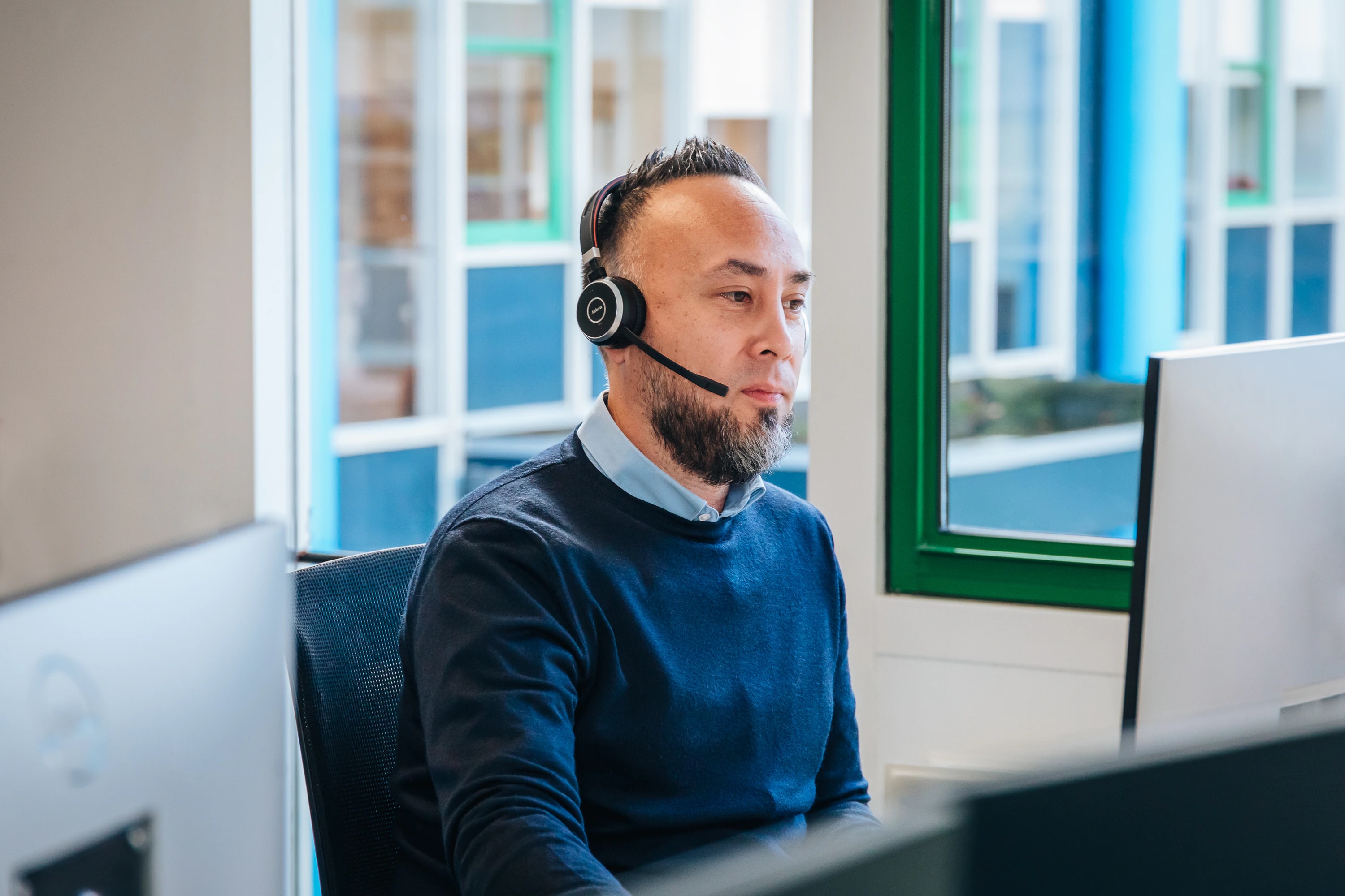Medewerker met headset aan het werk achter zijn computer