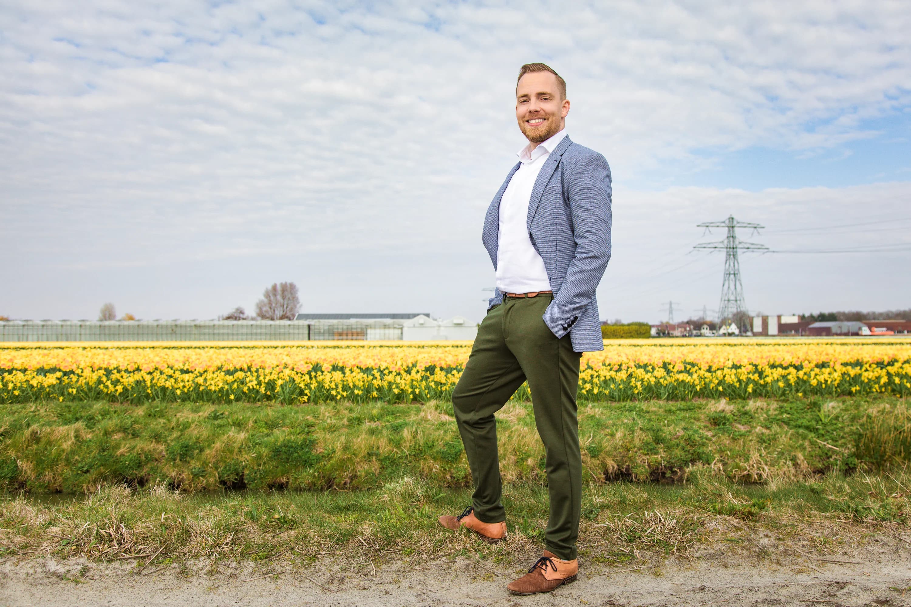 Ondernemer staat ontspannen buiten in een open landschap.