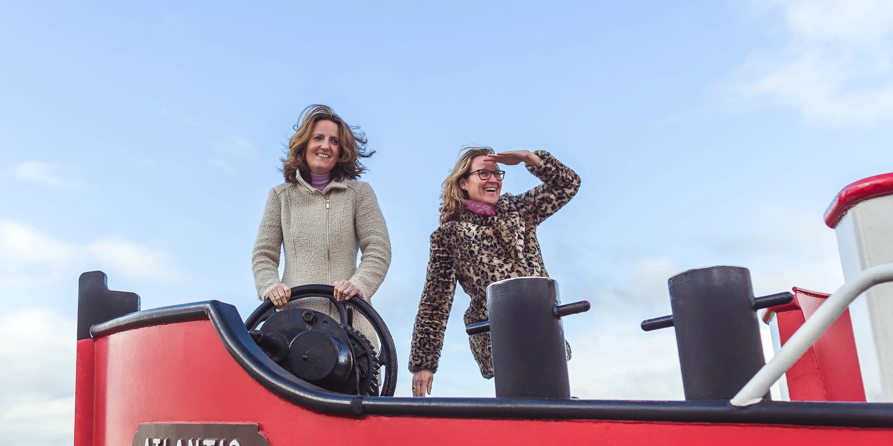 Twee vrouwen staan ontspannen samen op een opvallende buitenlocatie.