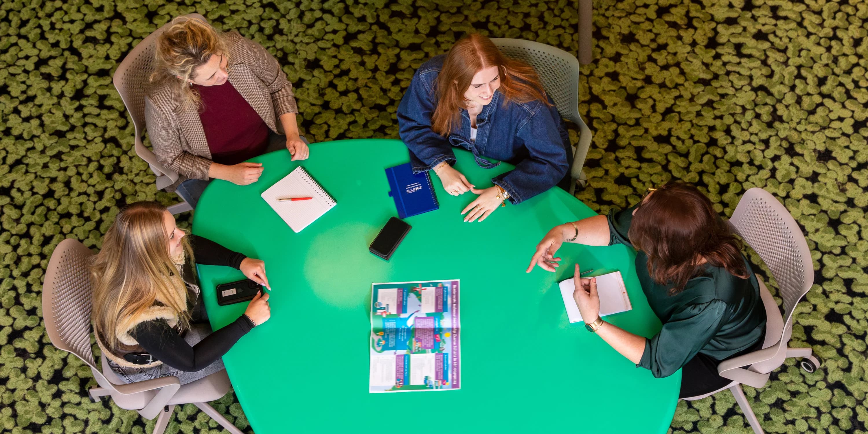 Team tijdens een gezamenlijk overleg aan tafel, van bovenaf gefotografeerd